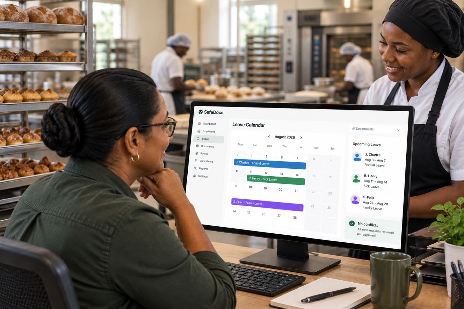 A smiling bakery manager reviewing a leave calendar with no conflicts on a monitor